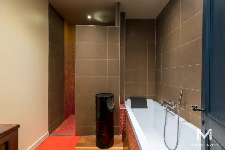 Salle de bain moderne avec baignoire et carrelage marron.