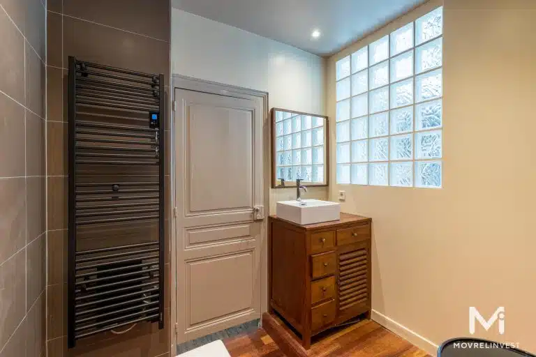 Salle de bain moderne avec fenêtre texturée et meuble bois.