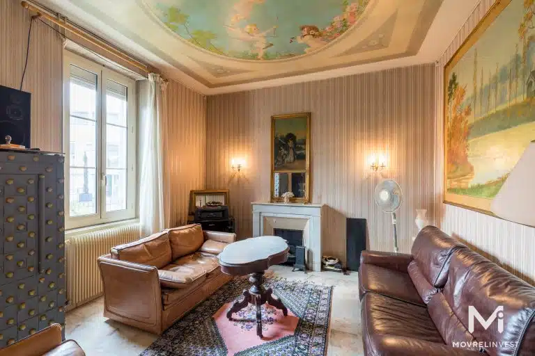 Salon élégant avec plafond peint et cheminée.