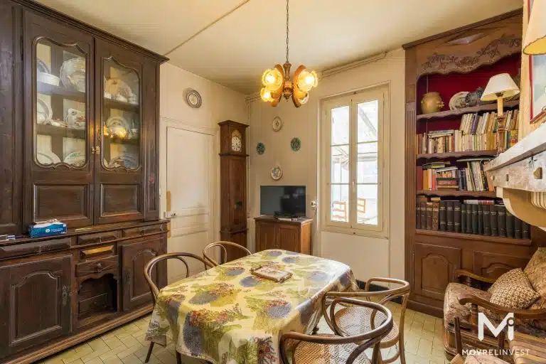 Salle à manger vintage avec bibliothèque et vaisselier en bois.