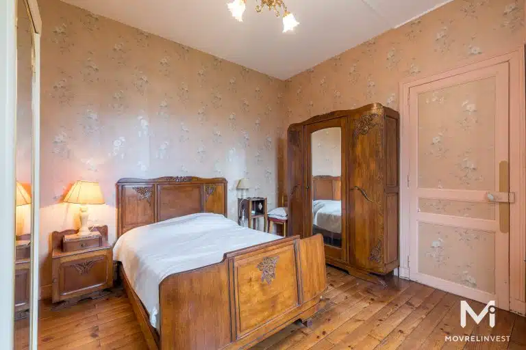Chambre vintage avec lit en bois et papier peint floral.