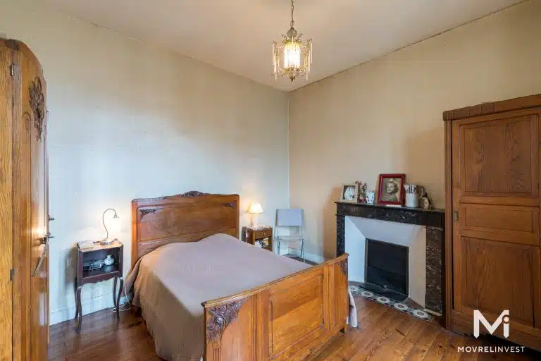 Chambre vintage lumineuse avec cheminée et boiseries.