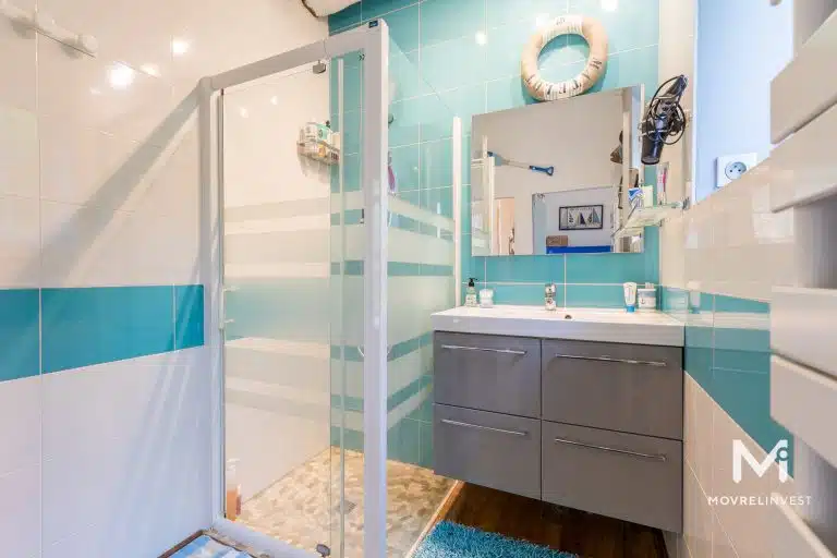 Salle de bain moderne avec douche en verre et meuble.