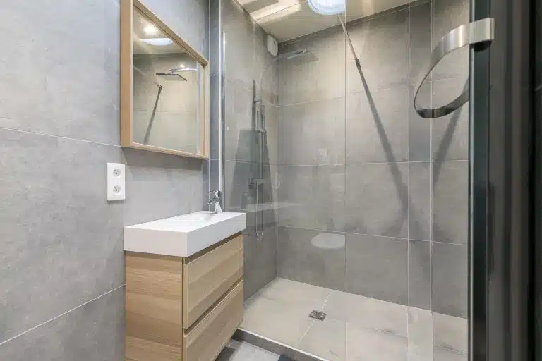 Salle de bain moderne avec douche italienne et miroir.
