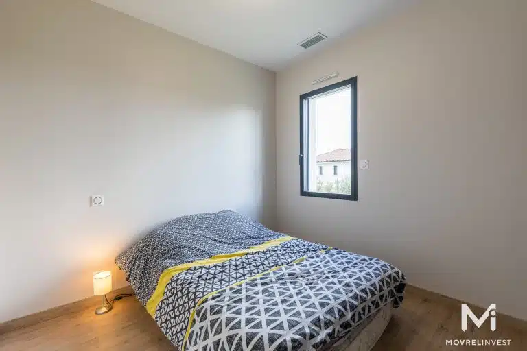 Chambre minimaliste épurée avec lit simple et lampe.