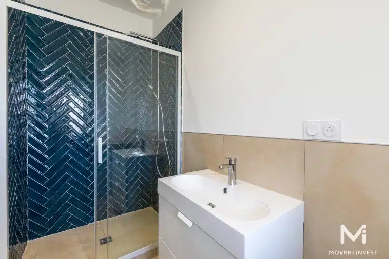 Salle de bain moderne avec douche et lavabo.