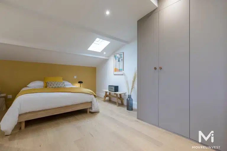 Chambre moderne avec mur jaune et parquet clair.
