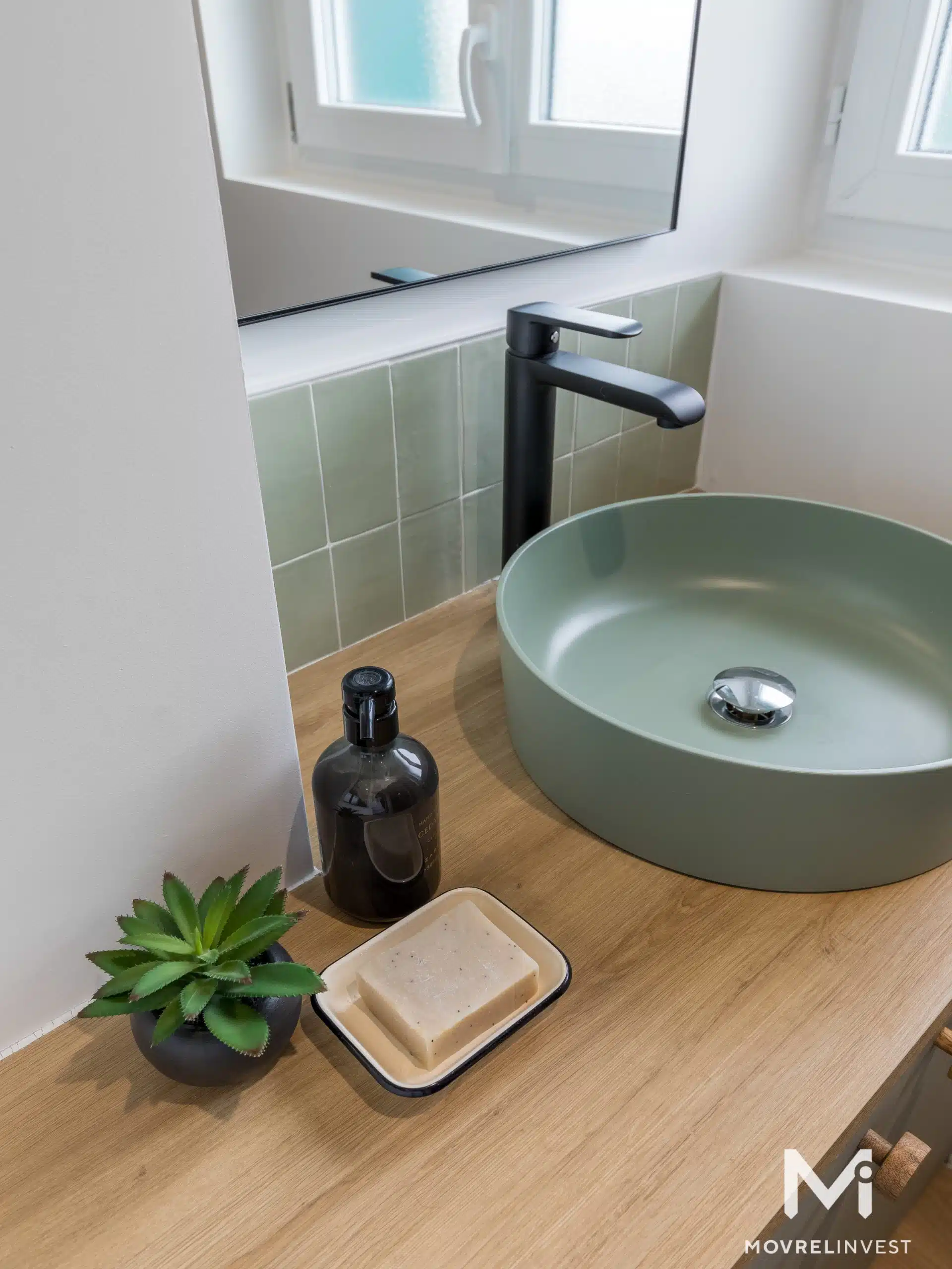 Salle de bain moderne avec vasque verte et robinet noir.