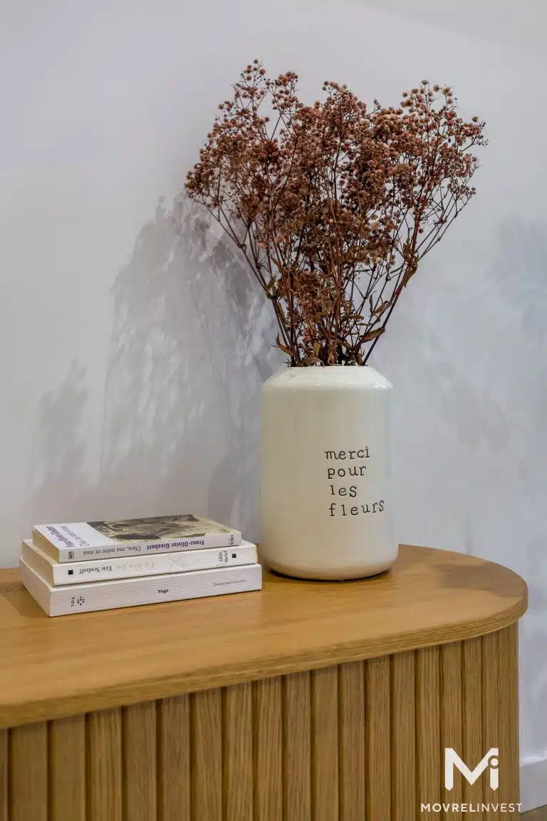 Vase décoratif et livres sur table en bois.