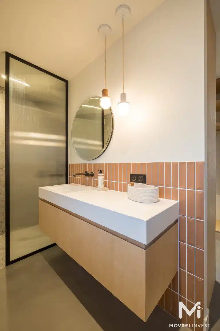 Salle de bain moderne épurée avec miroir rond.