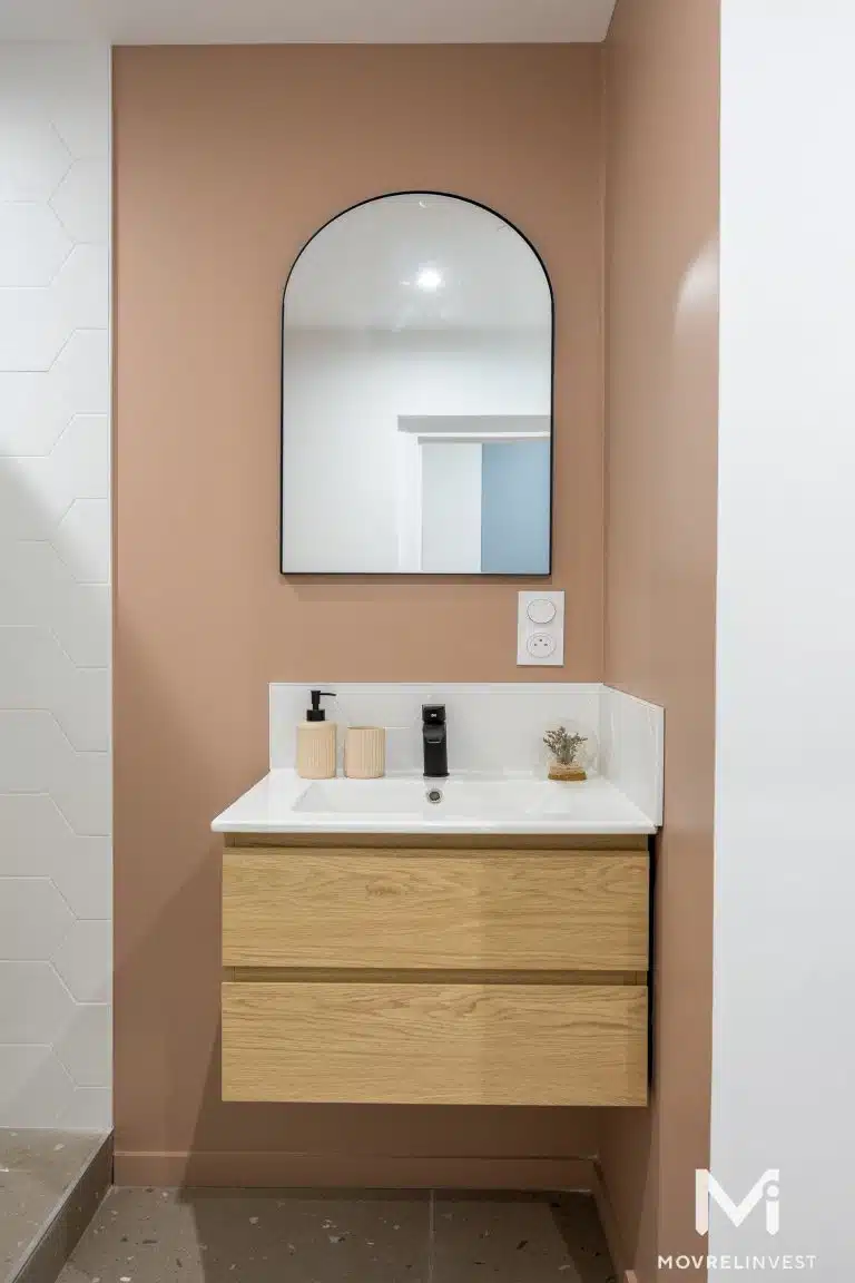 Salle de bain moderne avec miroir arrondi et meuble bois.