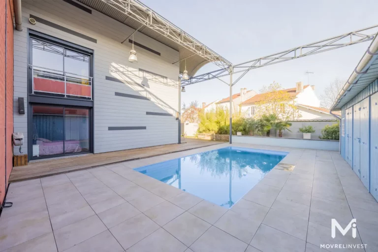 Maison moderne avec piscine extérieure et terrasse ensoleillée.