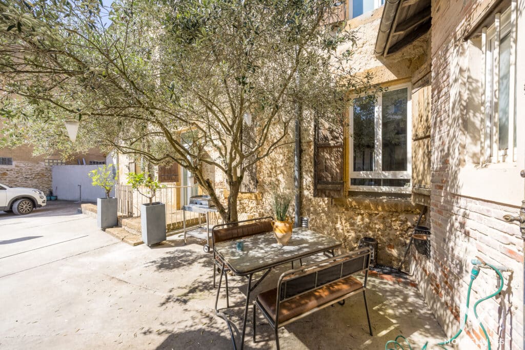 Cour pavée avec olivier et table à l'extérieur