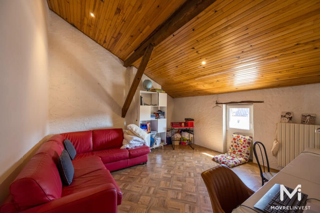 Salon spacieux avec canapé rouge et plafond en bois