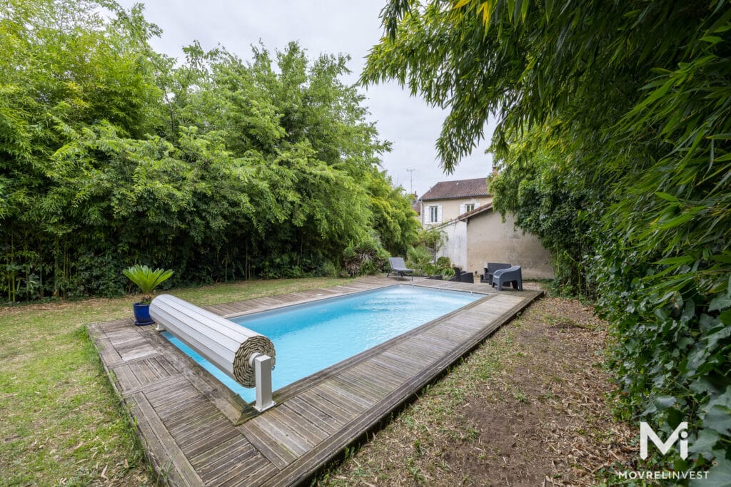 Jardin verdoyant avec piscine et terrasse en bois