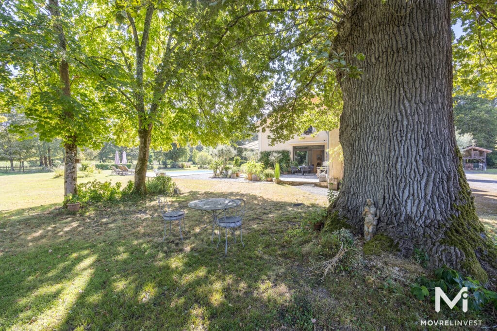 Maison paisible avec jardin et grands arbres.