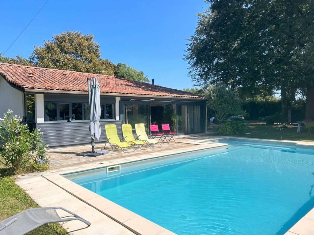 Maison avec piscine et chaises colorées sous soleil