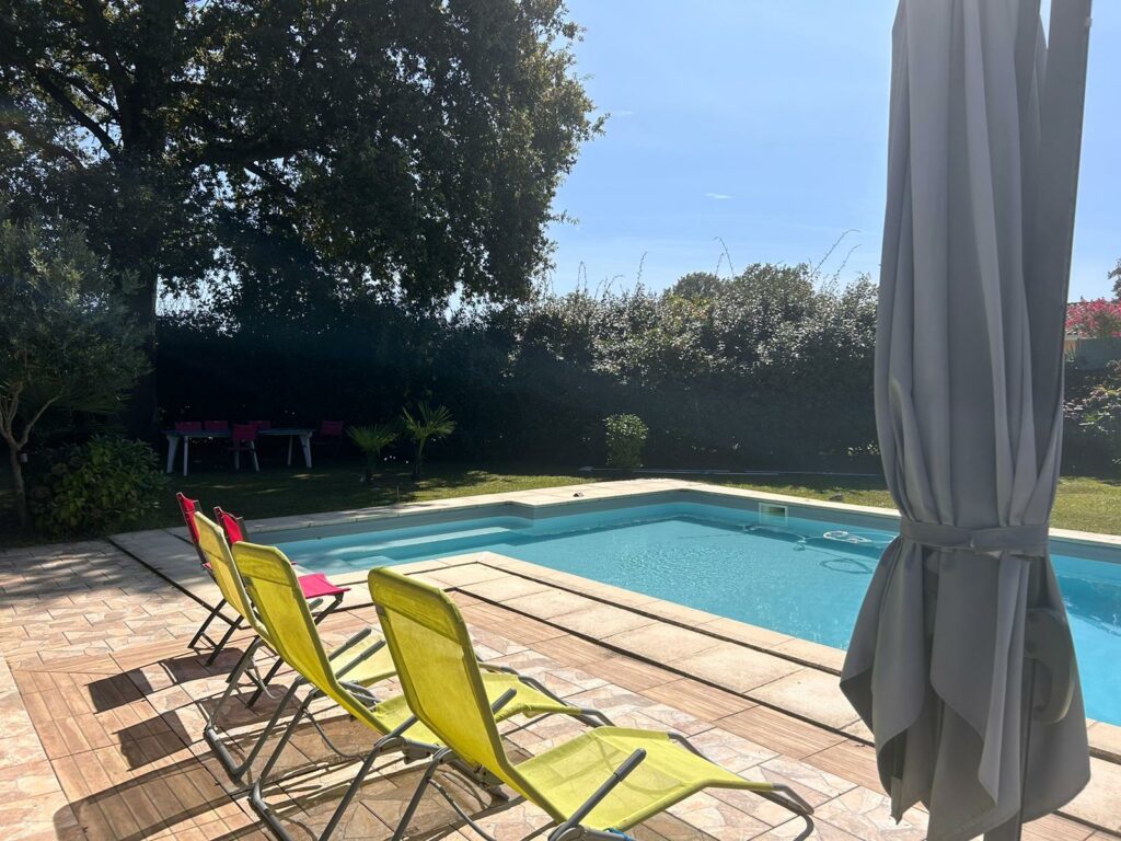 Piscine extérieure avec chaises longues et jardin ensoleillé