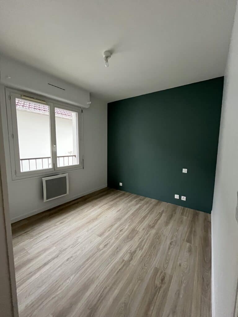 Chambre vide avec mur vert et sol en bois clair