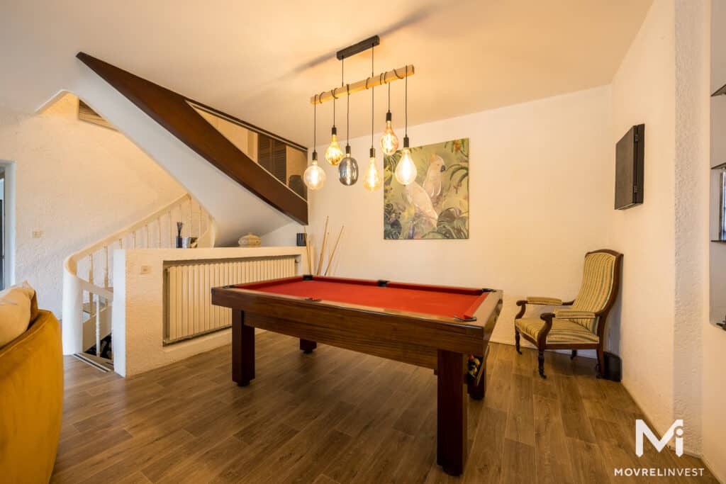 Salle de jeux avec billard et escalier, éclairage chaleureux