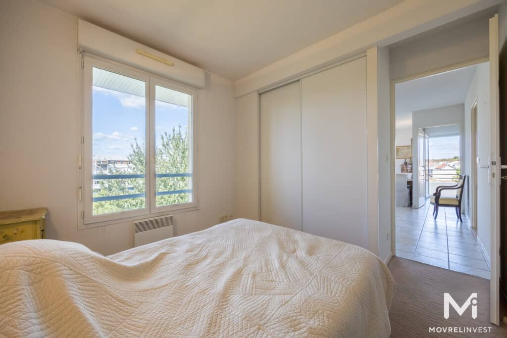 Chambre lumineuse avec grand lit et fenêtre ouverte