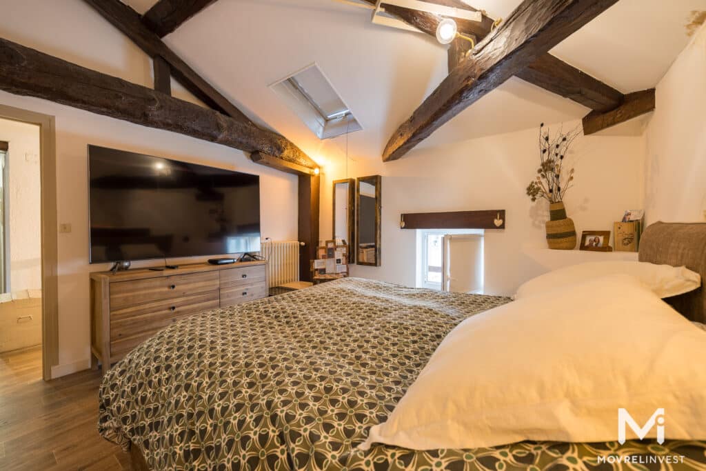 Chambre rustique avec poutres en bois et lit double.