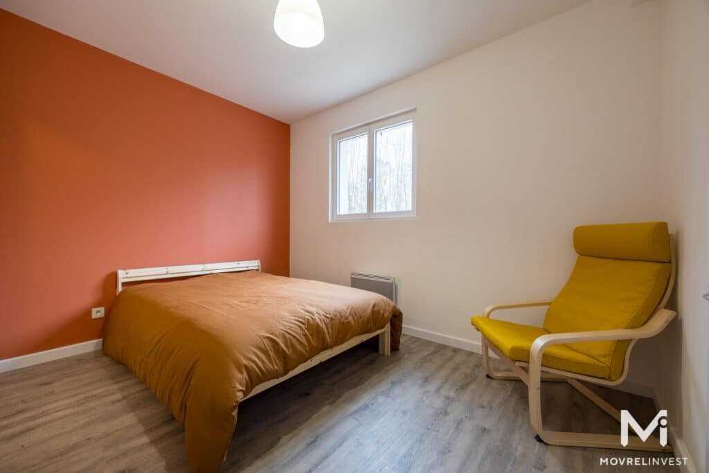 Chambre moderne avec mur orange et fauteuil jaune