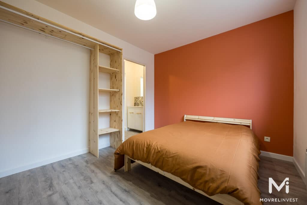 Chambre lumineuse avec mur orange et meubles en bois