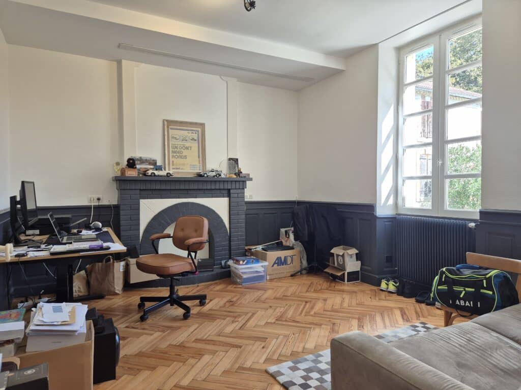 Bureau désordonné avec fenêtre, canapé et parquet