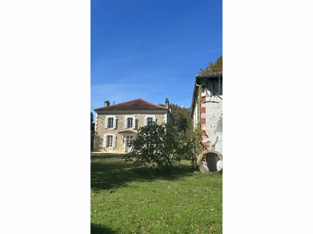 Manoir français classique avec jardin verdoyant et ciel bleu