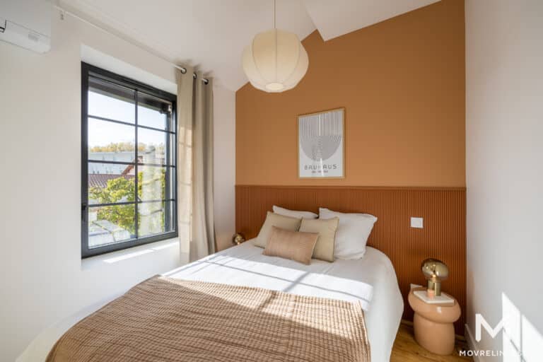 Chambre moderne avec mur orange et affiche Bauhaus