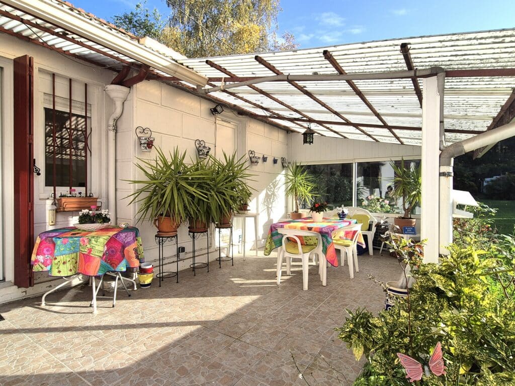 Terrasse ensoleillée avec mobilier coloré et plantes vertes